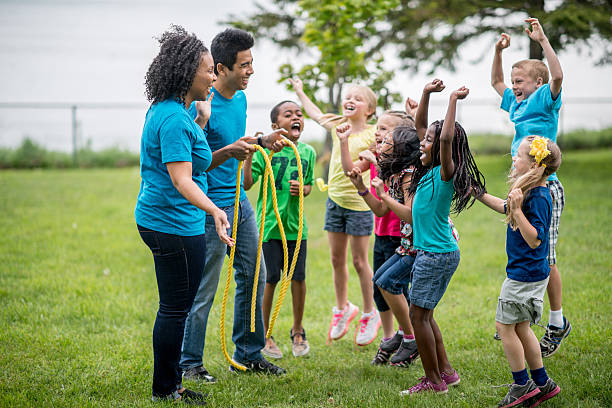diverse kids day camp playing tug of war.