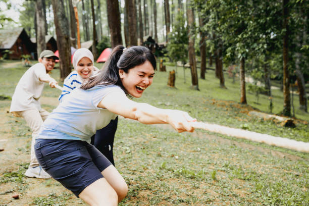 business team and creative team playing tug of war in the forest