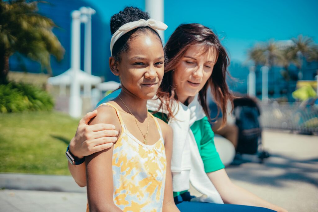 A joyful moment of mother and daughter bonding in a sunny park setting.