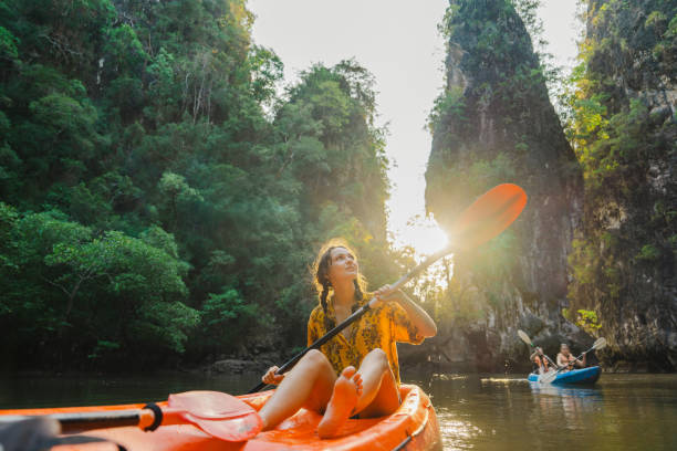 young caucasian woman sea kayaking among karst formations krabi
