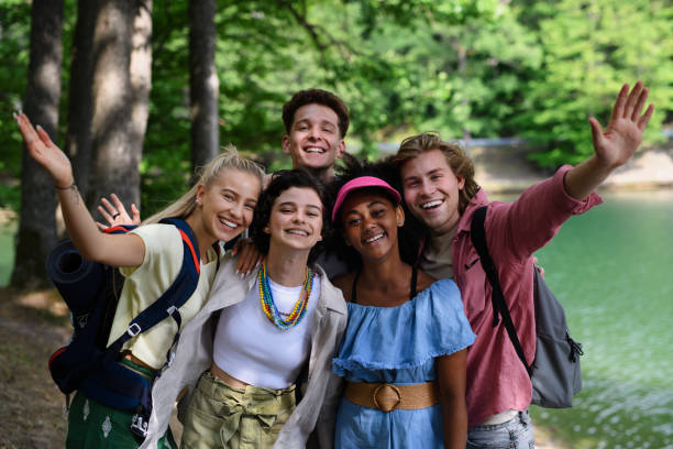 portrait of group of young friends on camping trip near lake in summer.